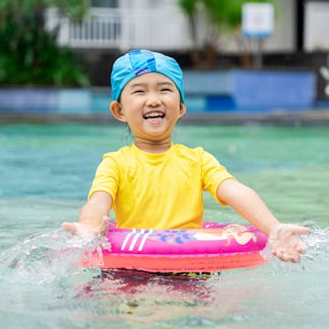 Cute little girl playing in a pool with a bright swimsuit. A new study found that bright neon colors...