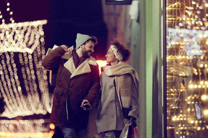 Young happy couple enjoying in a night walk and talk through the city while buying Christmas present...