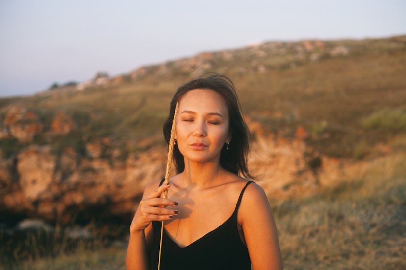 Young Asian woman wearing black dress enjoys sunset in summer, calm sea on the empty cliff, concept ...