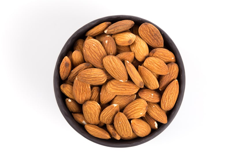 Black stone bowl of almonds nuts on a white background
