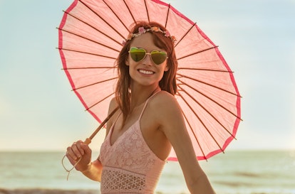 Portrait of happy Caucasian female wearing Bohemian dress and sunglasses with flower headband and ca...