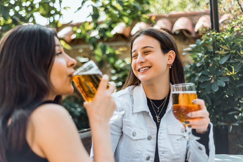 Two young woman drinking beer at the bar. Horizontal composition.