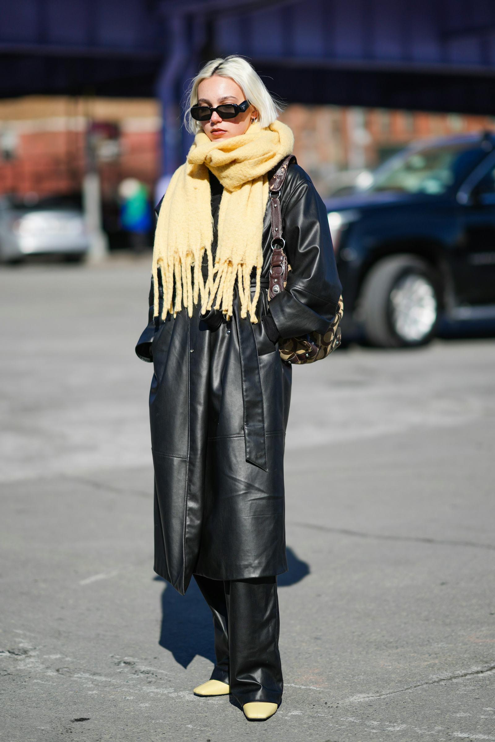 NEW YORK, NEW YORK - FEBRUARY 14: A guest wears black sunglasses from Prada, a pale yellow fringed w...