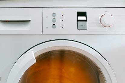 Modern washing machine turned on during the process of cleaning and washing clothes. Laundry room. H...