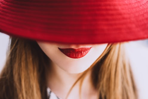 Beautiful fair-haired woman with lips painted red lipstick smiling in a red hat closing her eyes