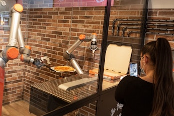 PARIS, FRANCE - JULY 09: A woman films her pizza being prepared at Pazzi, Paris' first robotic pizze...