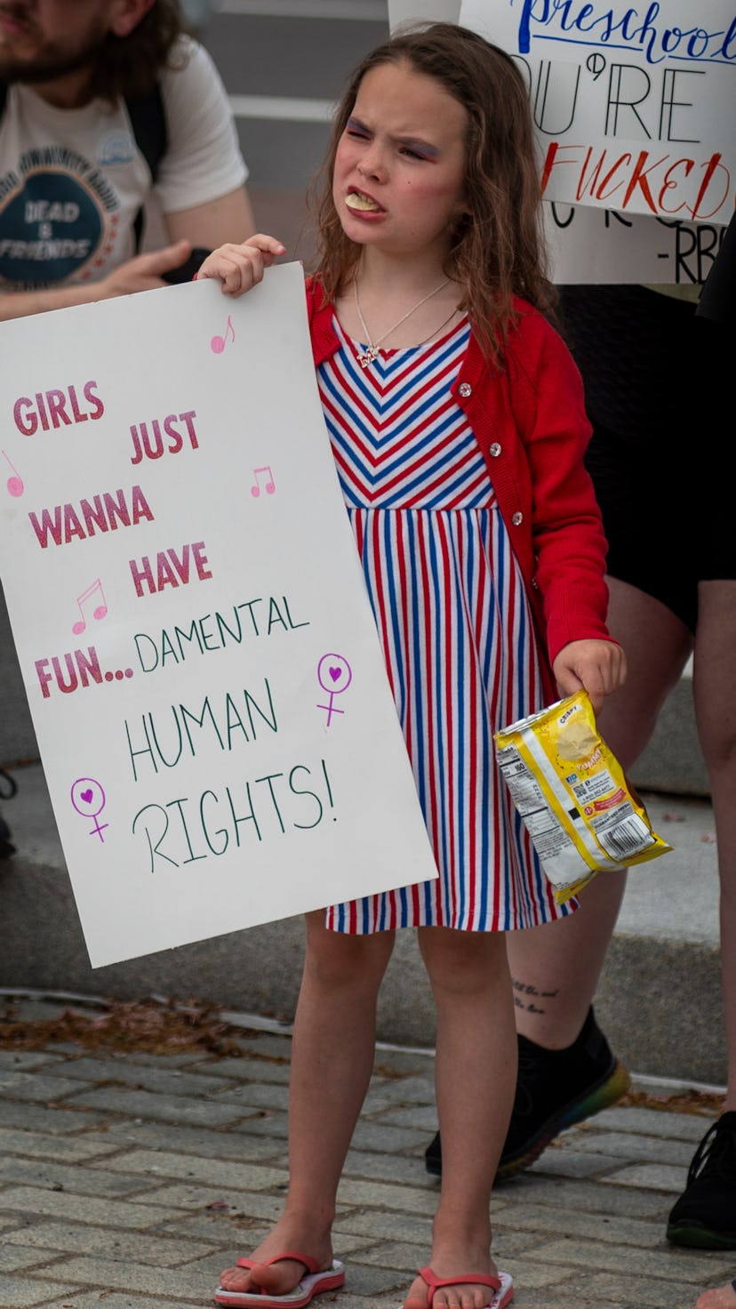 A girl in Wilkes-Barre, PA eats potato chips while holding a sign at an abortion rights rally readin...