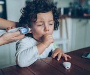 A mother checks her coughing child's temperature. A new study links the omicron variant to rising ca...