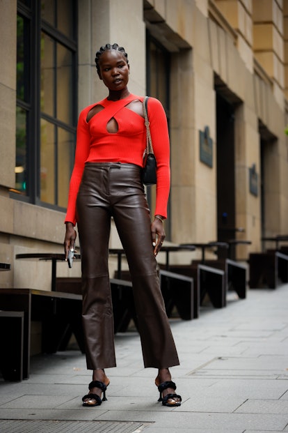 SYDNEY, AUSTRALIA - MAY 13: Malaan Ajang wearing a red cut-out knit top and dark brown leather pants...
