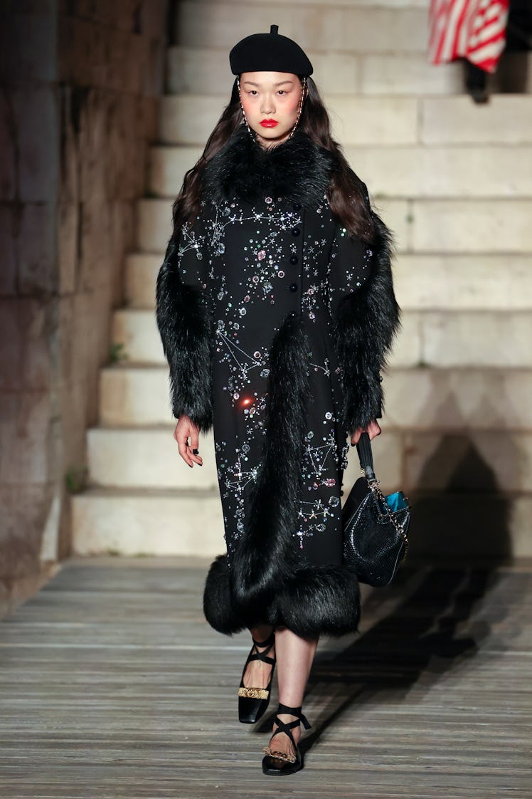 A model walking the runway during Gucci Cosmogonie at Castel Del Monte in a black gown and cap