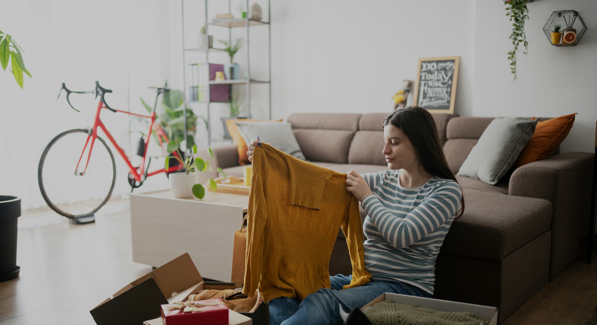 Young woman unboxing purchased clothes from online shopping event.