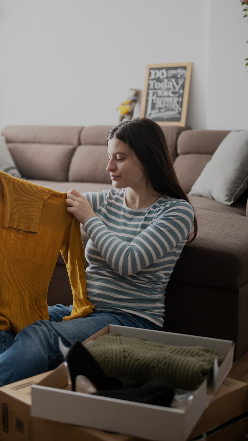 Young woman unboxing purchased clothes from online shopping event.