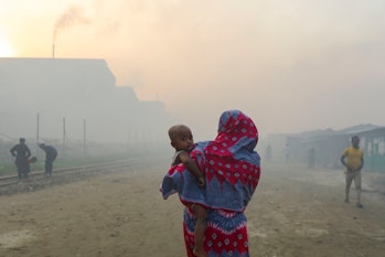 Women and children are vulnerable condition an air polluted area as smoke rises from a re-rolling mi...