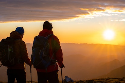 Two hikers on a mountain watching a sunset and they have a healthy relationship with their past