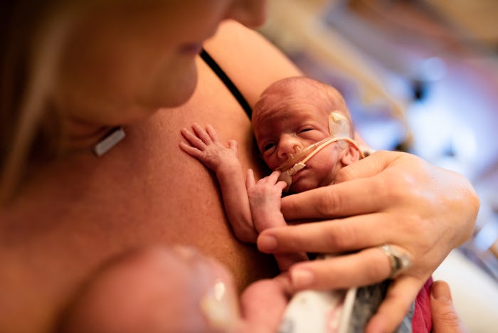 NICU premature twins are both held by mother on chest in NICU.