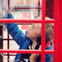 Two little boys trying to use a telephone in an old fashioned phone box