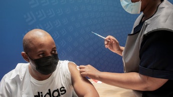 A man receives a dose of the Pfizer/BioNTech vaccine against COVID-19 at Discovery vaccination site ...