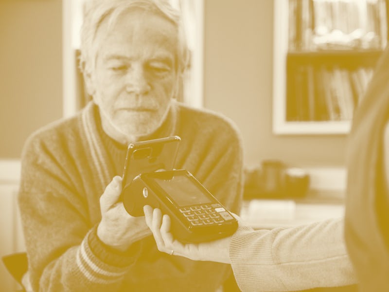 Senior man paying with contactless using mobile phone at cafe