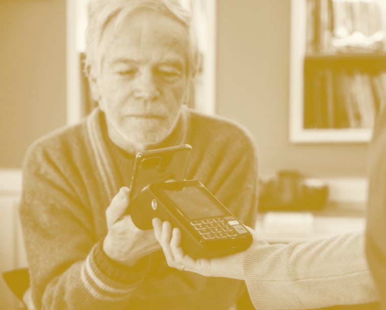 Senior man paying with contactless using mobile phone at cafe