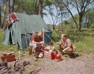 A father and son help themselves to sandwiches from their Kiltie coolbox during a camping trip, 1956...