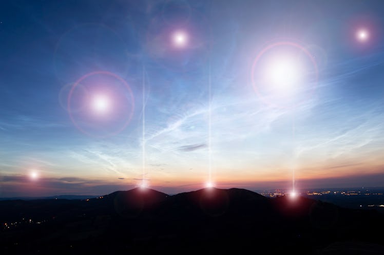 A science fiction concept. Of glowing UFO lights floating above hills and a city just before sunrise...