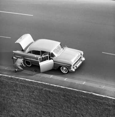 Automobiliste changeant une roue de sa voiture après une crevaison, circa 1950. (Photo by Paul POUGN...
