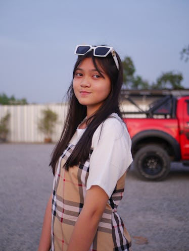 一个女孩站在外面,她的额头上戴太阳镜。