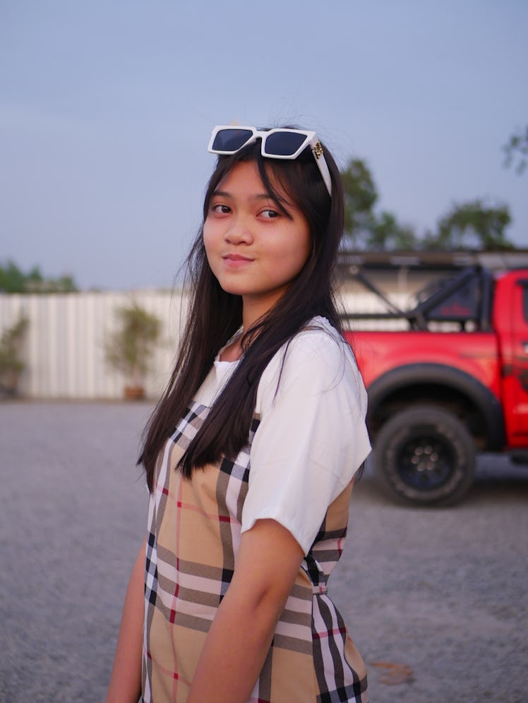 A girl standing outside, with sunglasses on her forehead.