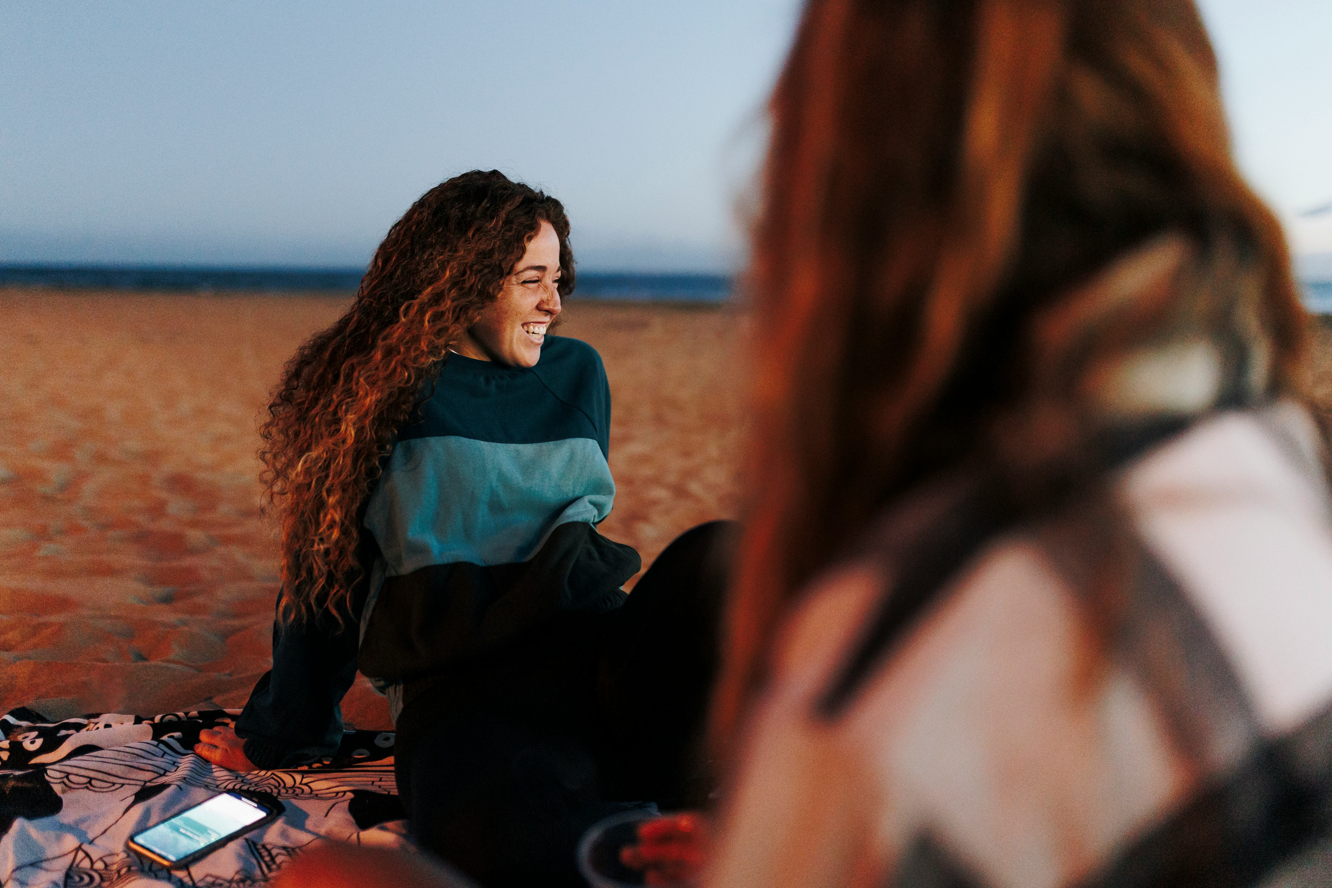 Woman smiles on the beach. may 2022 new moon dos and don'ts.