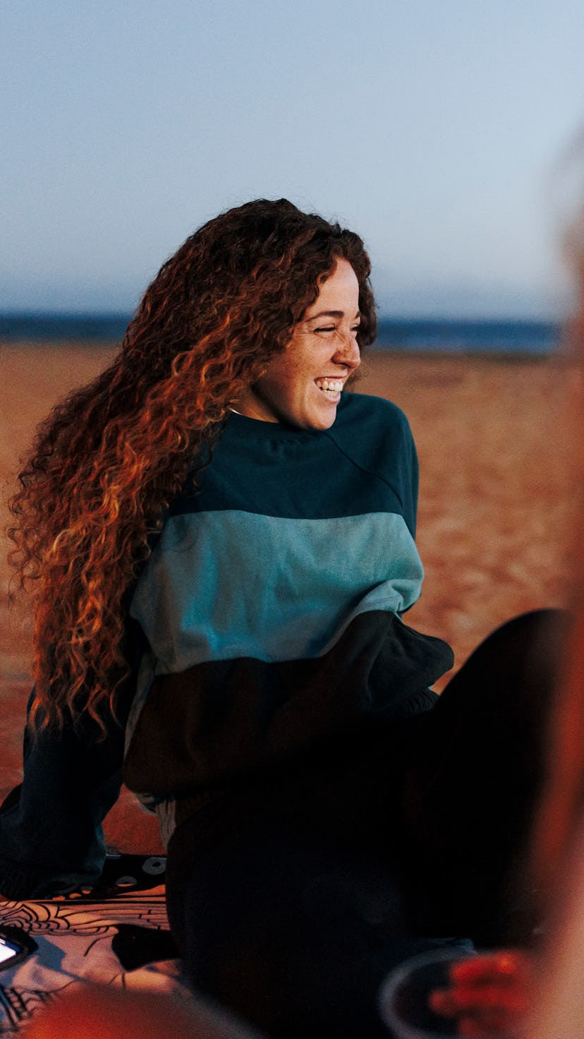Woman smiles on the beach. may 2022 new moon dos and don'ts.