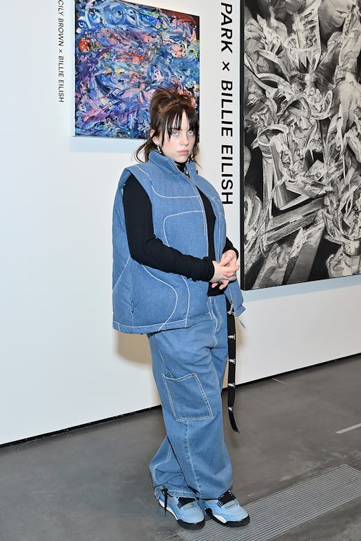Billie Eilish wearing a denim vest and baggy jeans with blue nike jordan retro 4 sneakers on January...