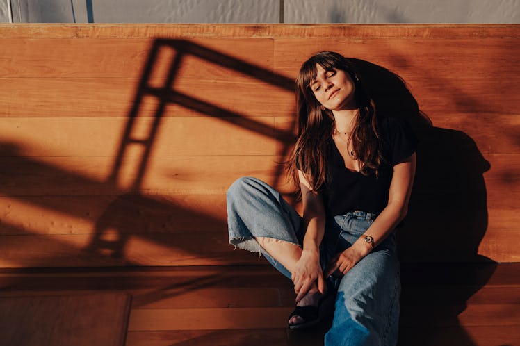 young woman relaxes on a bench eyes closed as she thinks about the planets retrograde in june 2022