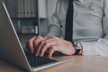 男人用手在他的笔记本电脑键盘