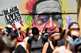 DENVER, COLORADO - MAY 7: Marchers walk by a mural of George Floyd painted on a wall along Colfax Av...