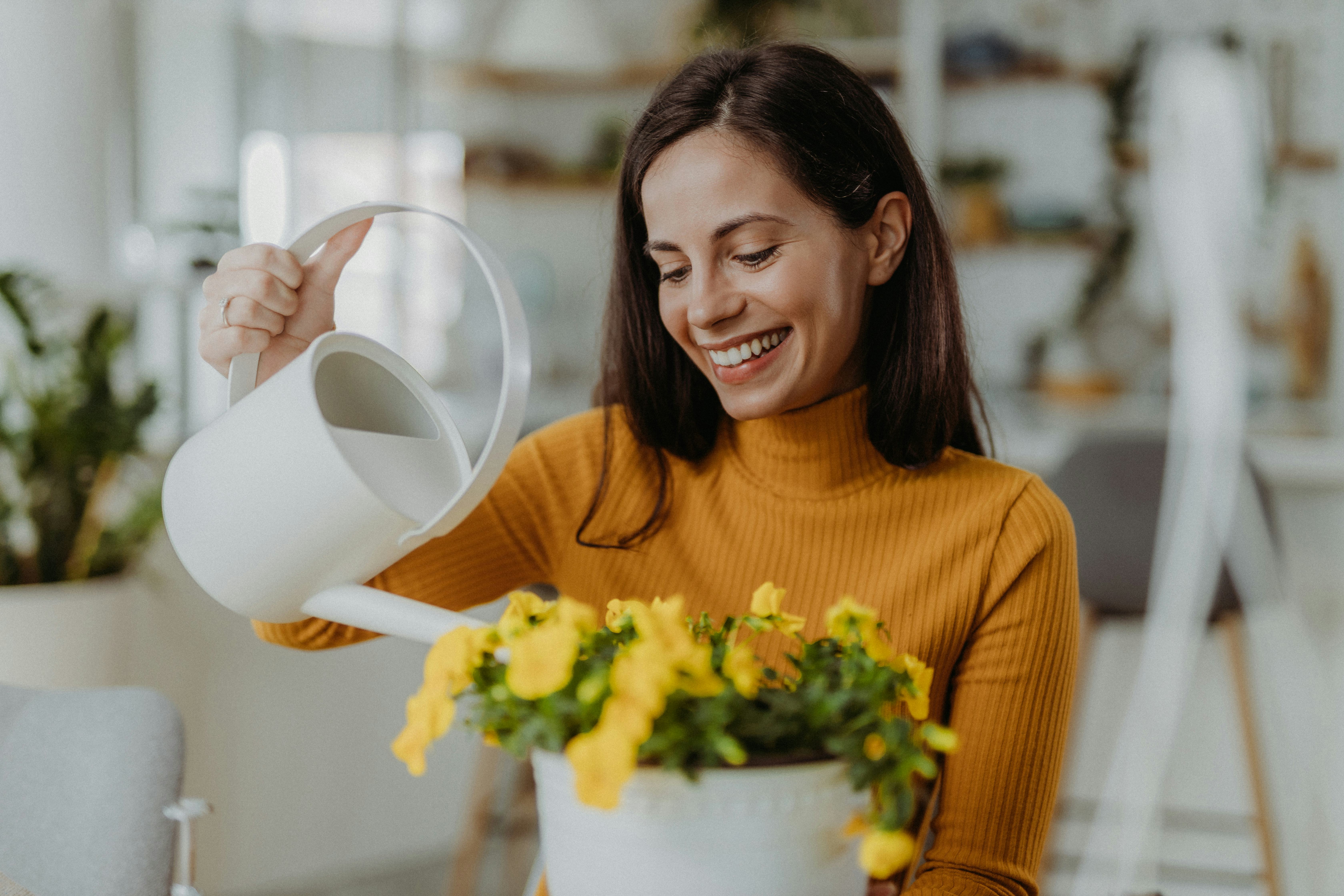 Young woman watering and planting flowers at home