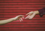 Two hands touch each other in front of a brick wall