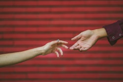 Two hands touch each other in front of a brick wall