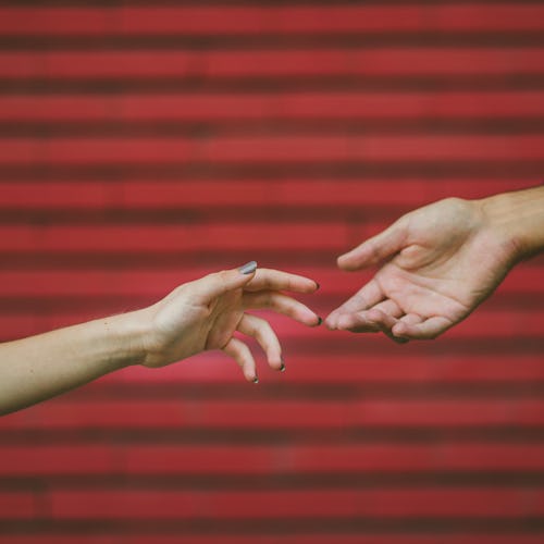 Two hands touch each other in front of a brick wall