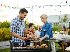 Happy man serving meat while woman holding board. Couple is celebrating Asado in backyard. They are ...