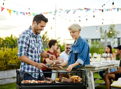 Happy man serving meat while woman holding board. Couple is celebrating Asado in backyard. They are ...