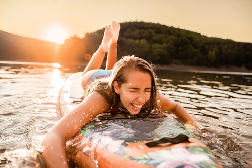 Woman paddleboarding on a lake at sunset. Here’s your may 26 zodiac sign daily horoscope. 