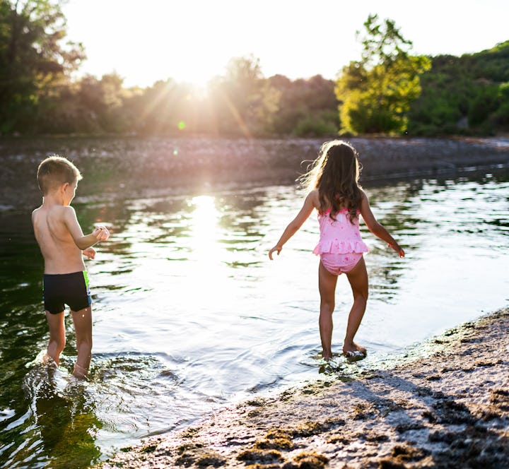 Beautiful boy and girl having fun on a river during hot summer day.