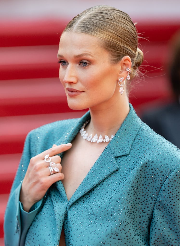 Toni Garrn at the screening of "Triangle Of Sadness" in a turquoise blazer, floral diamond earrings,...