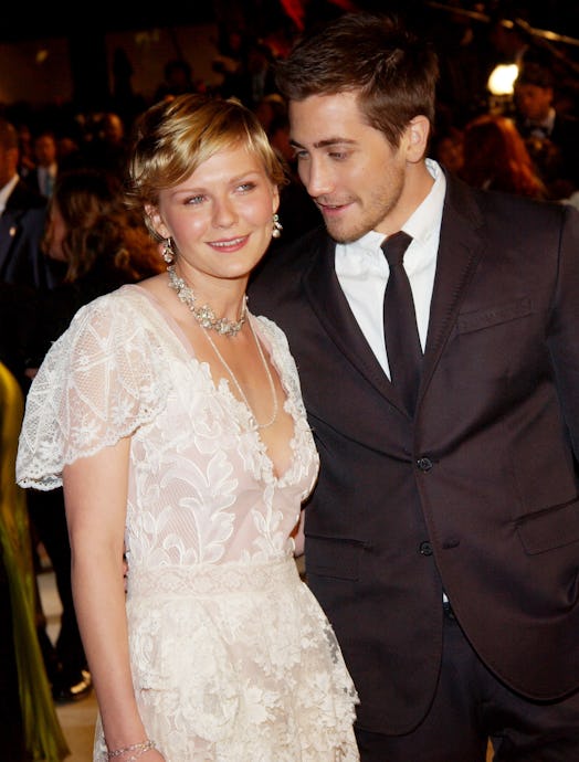 Kirsten Dunst and Jake Gyllenhaal pose together. dunst wears a cream lace dress and gyllenhaal wears...