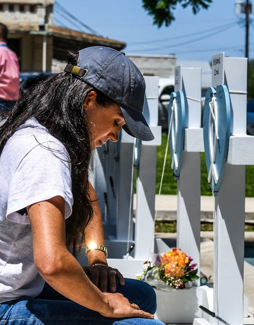 Britain's Meghan, Duchess of Sussex, places flowers as she mourns at a makeshift memorial outside Uv...