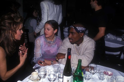 Madonna and Tupac Shakur sit at a table listening to Raquel Welch. Madonna wears a lilac top and Tup...