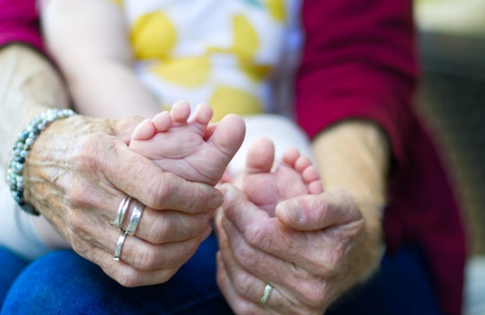 Hands of grandmother holding onto baby feet