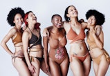 Studio shot of a group of beautiful young women in posing together in swimwear against a gray backgr...
