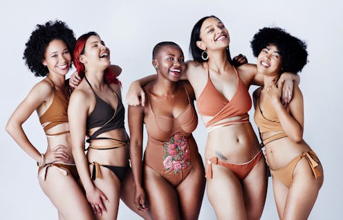Studio shot of a group of beautiful young women in posing together in swimwear against a gray backgr...