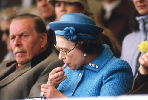 Queen Elizabeth II puts on lipstick in the Royal Box at the Windsor Horse Show on May 11, 1985. Prin...